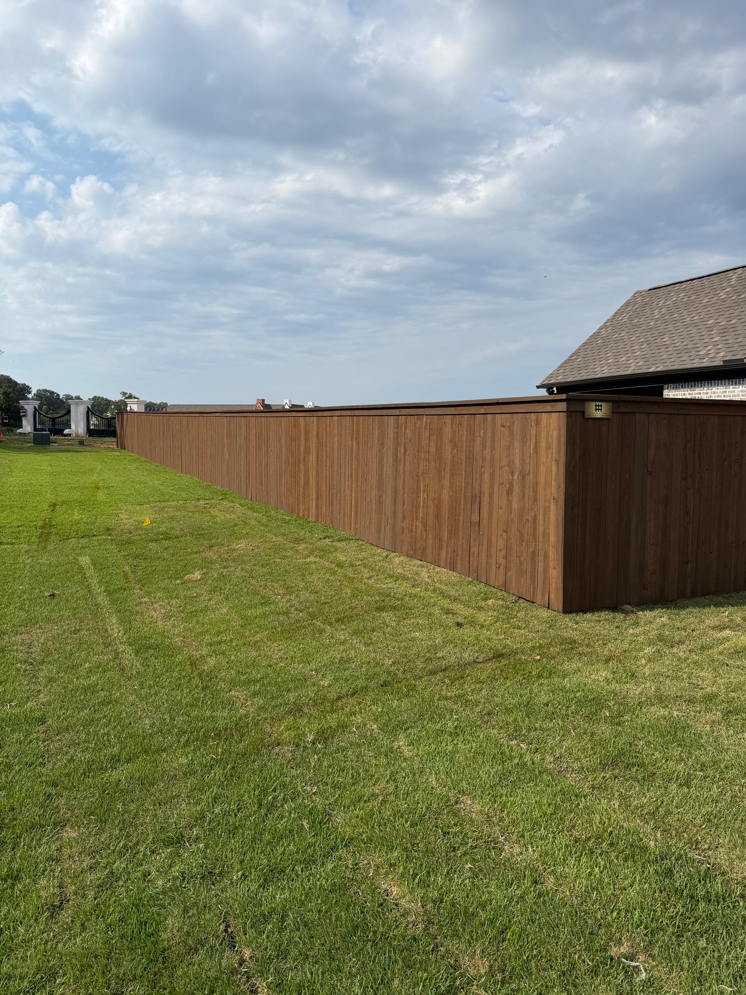 Pre-stained cedar cap and trim privacy fence running the length of an open backyard