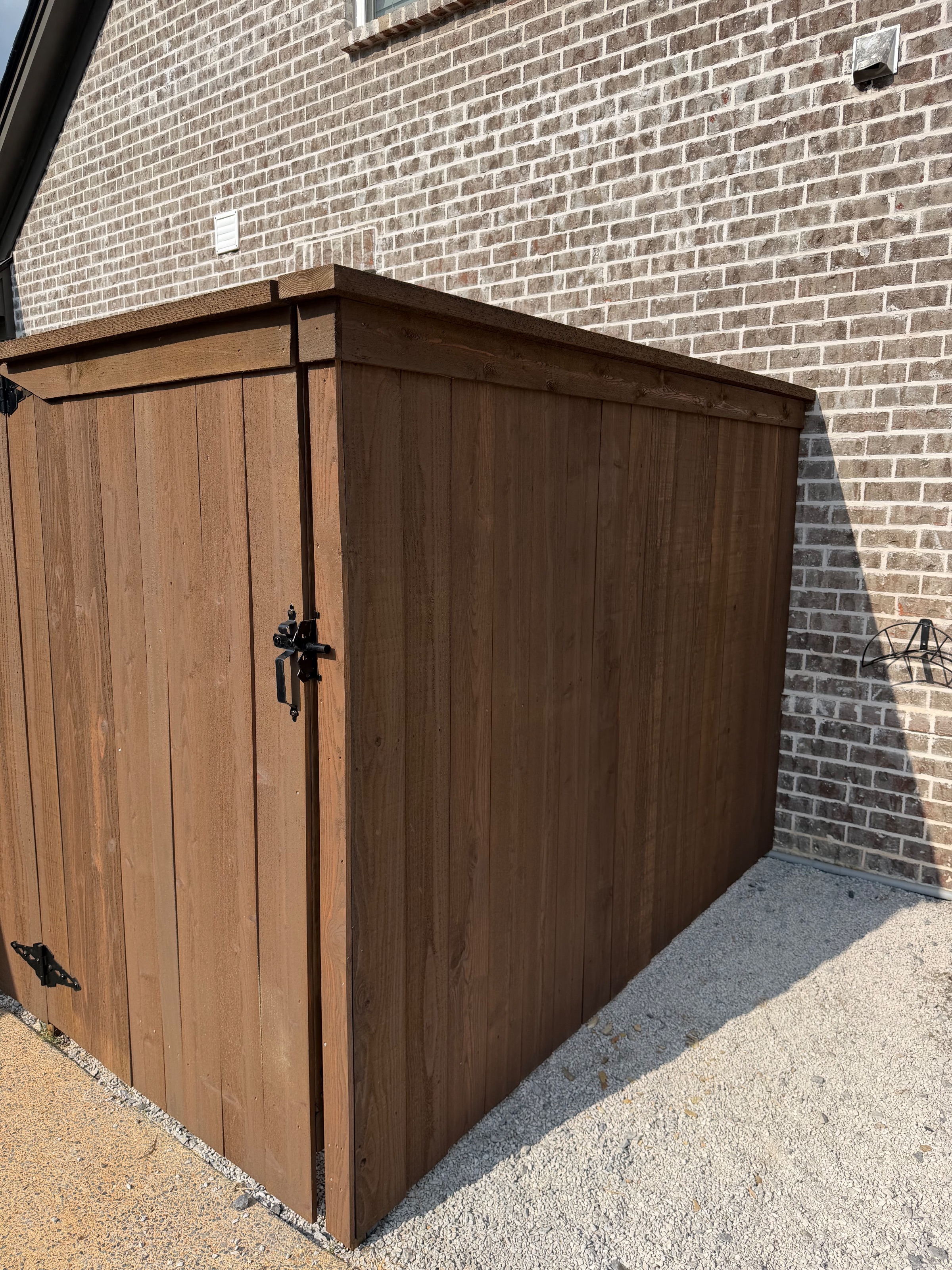 Pre-stained cedar walk gate on black strap hinges beside a brick home