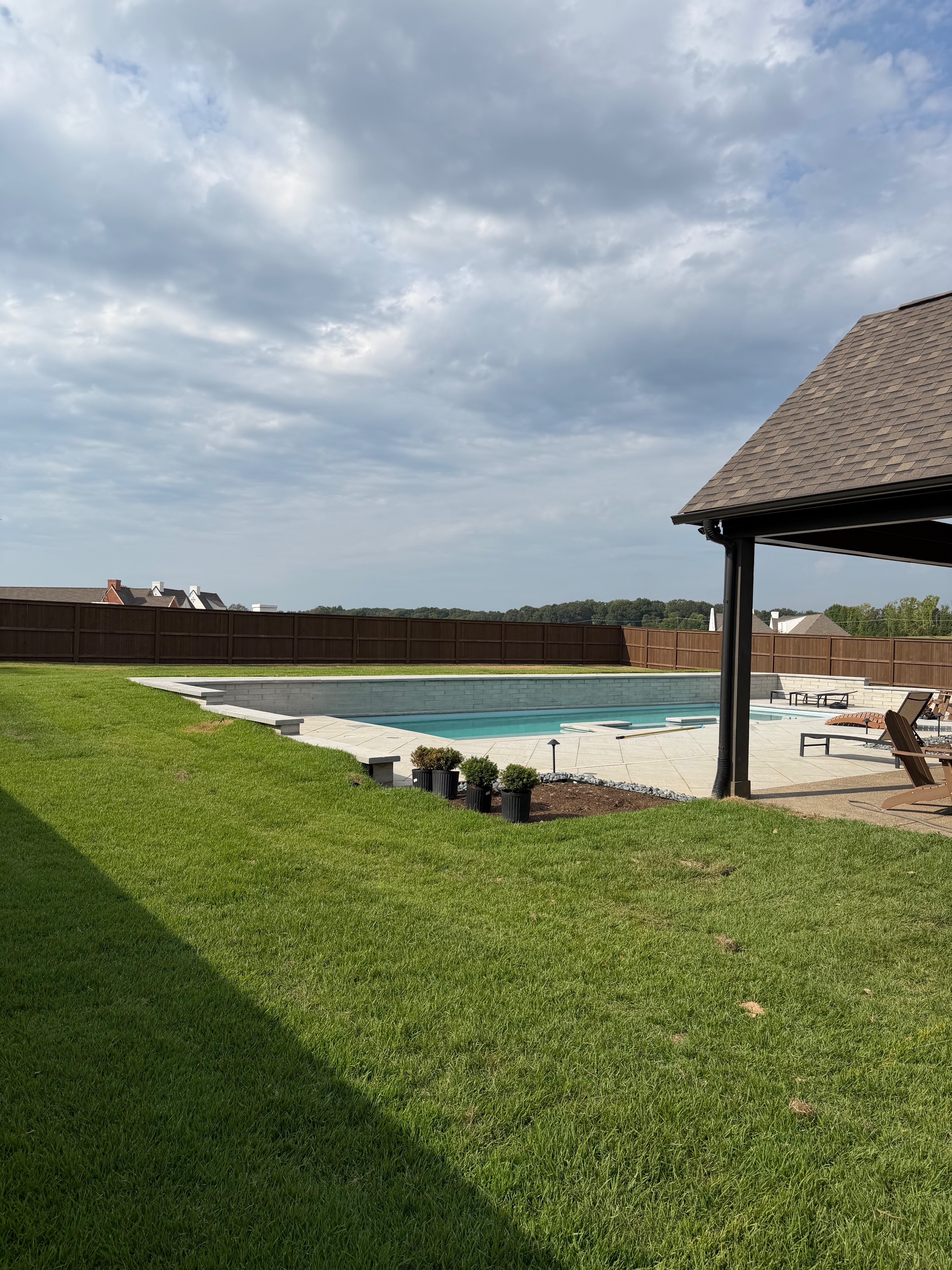 Pre-stained cedar privacy fence enclosing a backyard with an in-ground pool and covered pavilion