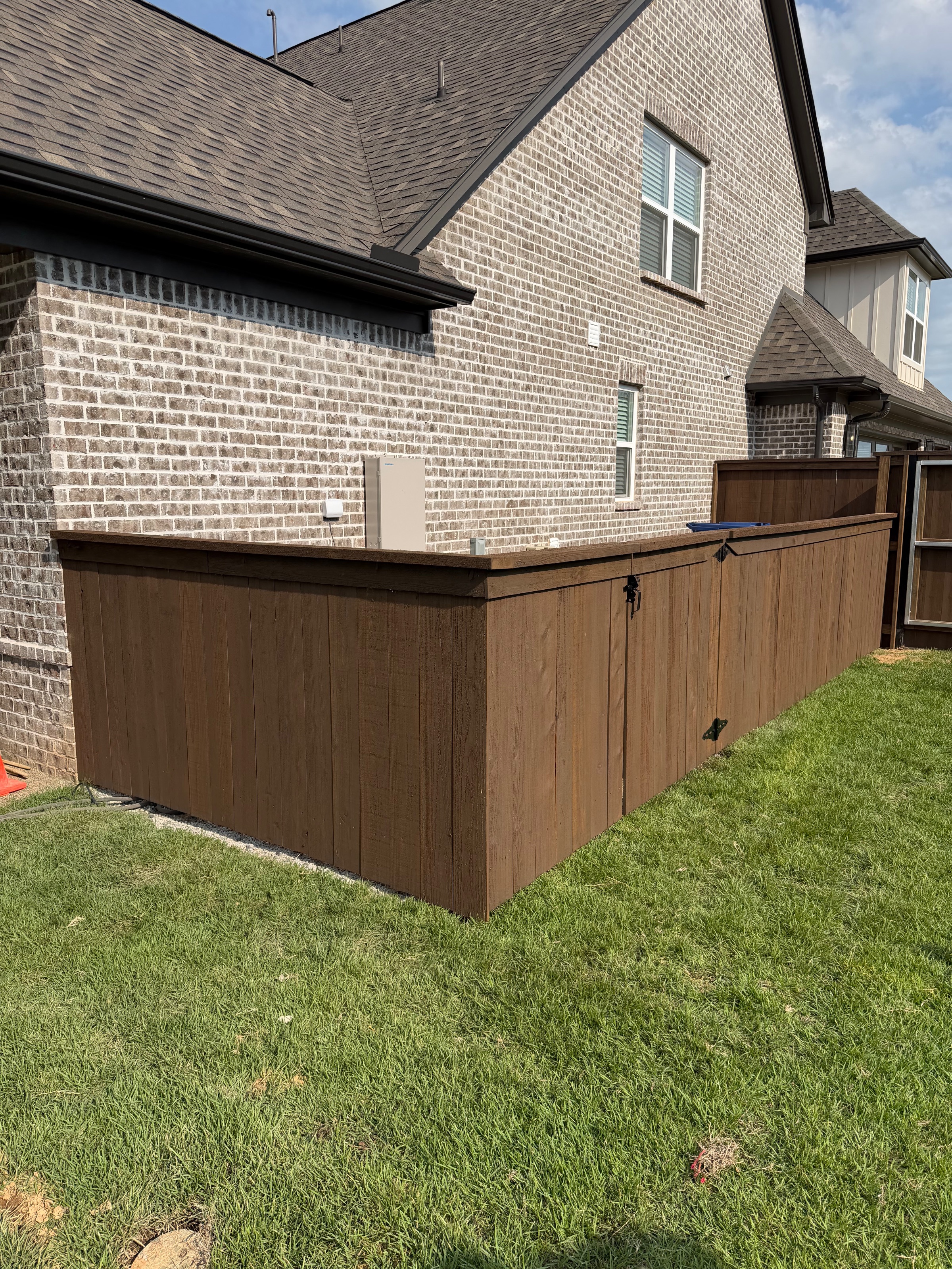 Pre-stained cedar fence corner and gate return along the side of a brick home